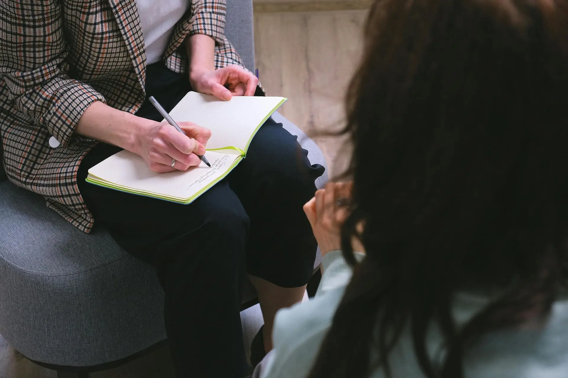 Psychoterapeutka robiąca notatki podczas sesji z klientem – zdjęcie ilustrujące profesjonalną i empatyczną pracę w psychoterapii indywidualnej.